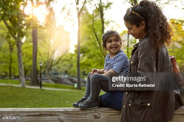 mother and daughter talking as the sun sets on central park - indian family vacation stock pictures, royalty-free photos & images