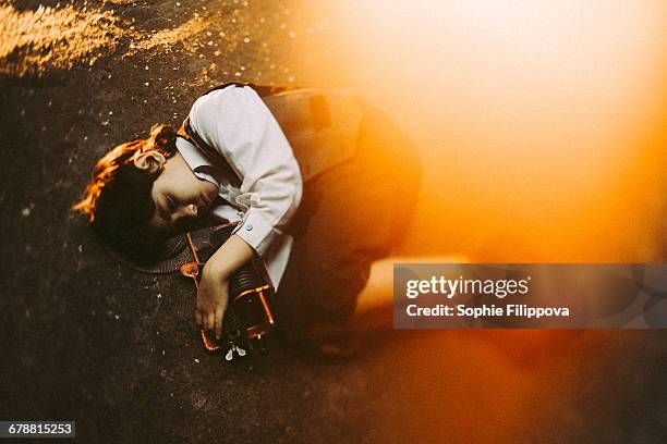 old-fashioned caucasian boy laying in street holding machinery - boy lying dead stockfoto's en -beelden