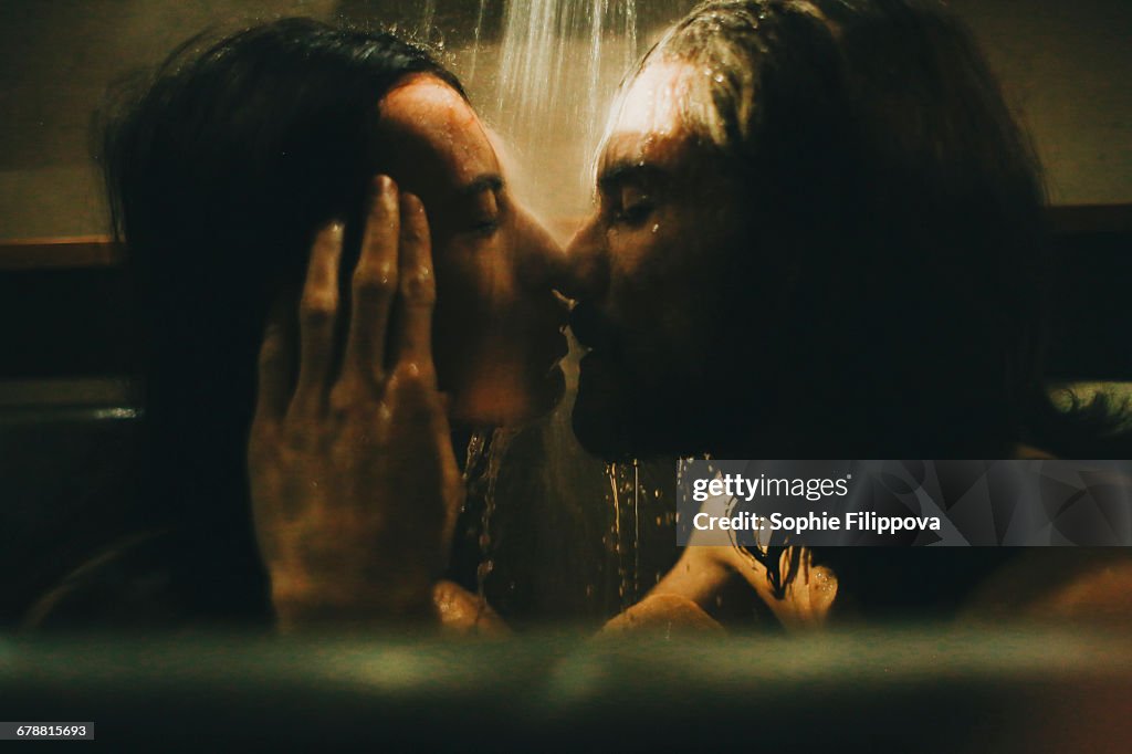 Caucasian couple relaxing in bathtub under shower