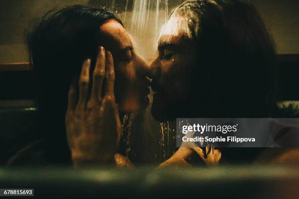 caucasian couple relaxing in bathtub under shower - couples kissing shower photos et images de collection