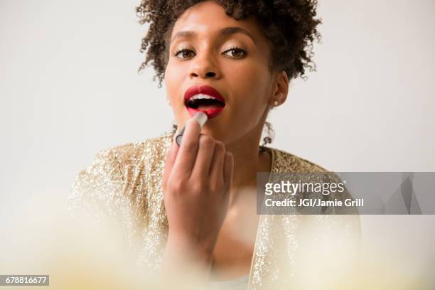 glamorous black woman applying red lipstick - rossetto foto e immagini stock