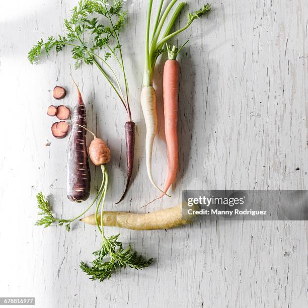 Variety of carrots on white wooden table