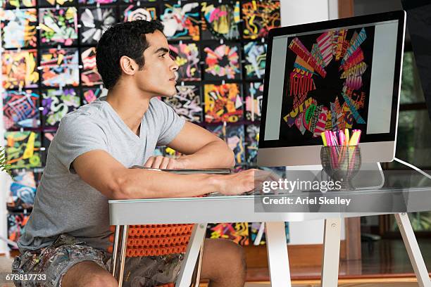 hispanic man wearing shorts using computer in art studio - graphic designer stock pictures, royalty-free photos & images