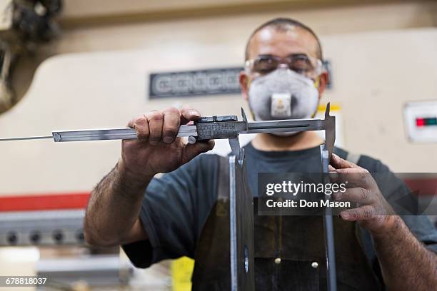 hispanic worker measuring metal with caliper in factory - making masks stock pictures, royalty-free photos & images