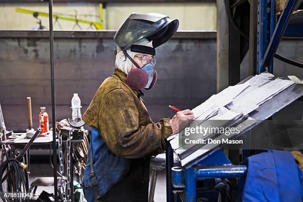 asian worker wearing mask writing on paperwork in factory - atemschutzmasken stock-fotos und bilder