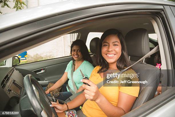 smiling hispanic mother and daughter posing in car - cinturón de seguridad fotografías e imágenes de stock