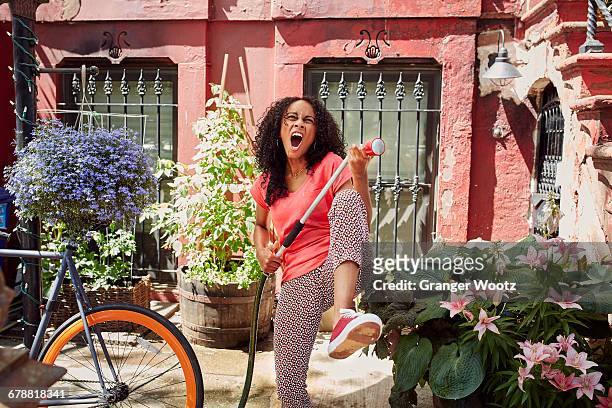 mixed race woman singing and playing air guitar in garden - it's all easy foto e immagini stock