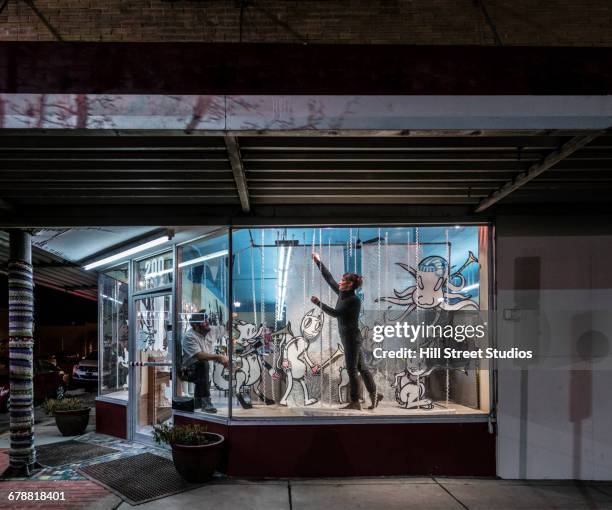 man and woman decorating display window in music store - night before imagens e fotografias de stock