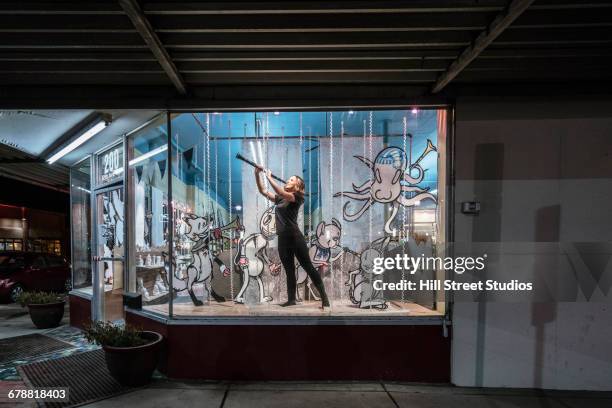 girl playing clarinet in display window of music store - loja de música imagens e fotografias de stock