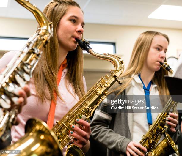 caucasian girls playing saxophones in music class - saxofoon stockfoto's en -beelden