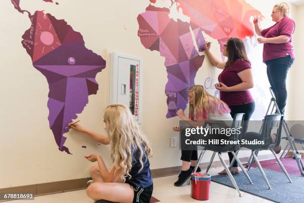 students painting mural of map on school wall - young artists unite stock pictures, royalty-free photos & images