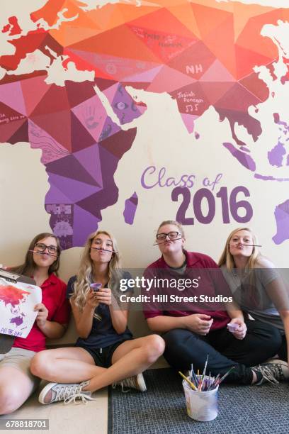 students using paintbrushes as mustaches under map mural - young artists unite fotografías e imágenes de stock