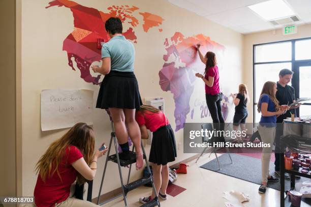 students painting mural of map on school wall - young artists unite stock pictures, royalty-free photos & images