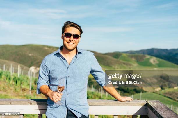 caucasian man leaning on balcony drinking wine - サンタイネス ストックフォトと画像