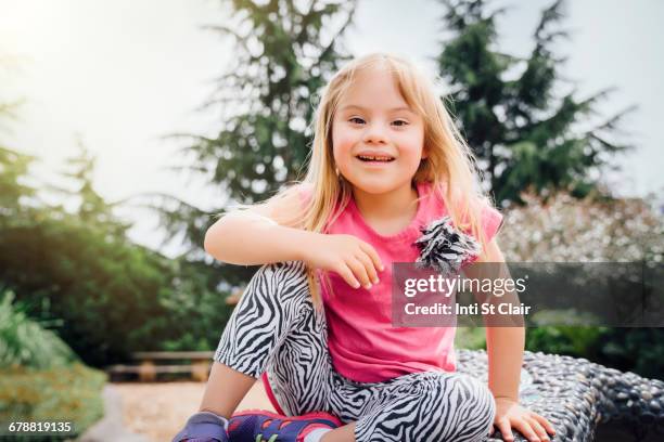 smiling mixed race girl sitting on bench - down syndrome girl stock pictures, royalty-free photos & images