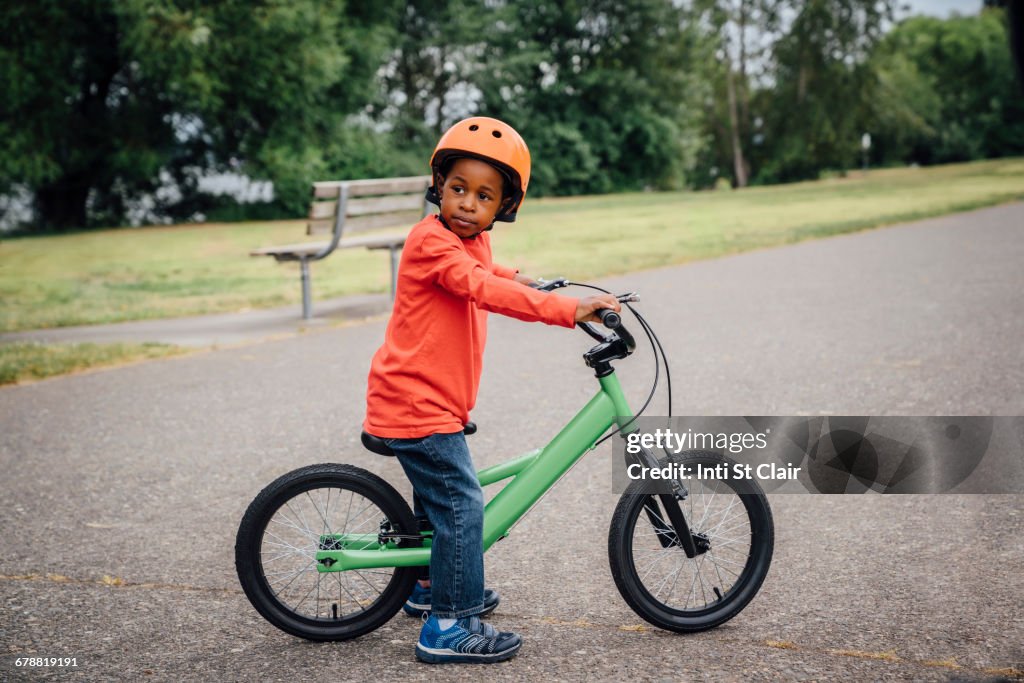 Black boy wearing helmet sitting on bicycle