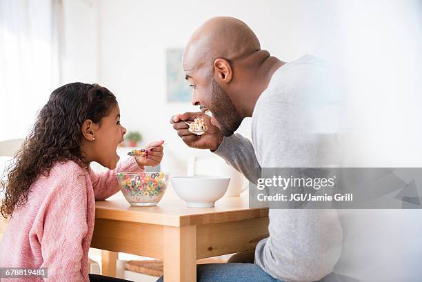 father and daughter eating cereal at table - eating cereal stock pictures, royalty-free photos & images