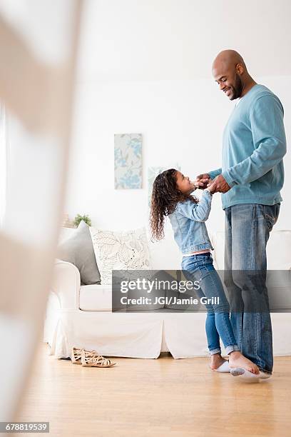 daughter standing on feet of father and dancing - kids feet in home stock-fotos und bilder
