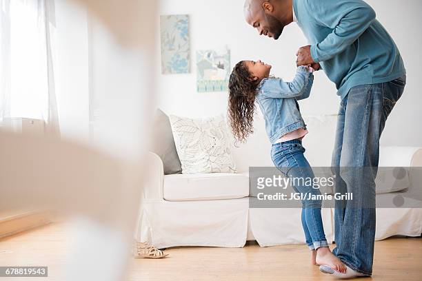 daughter standing on feet of father and dancing - girl in black jeans stockfoto's en -beelden