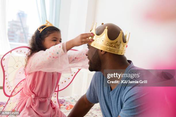 daughter wearing costume placing crown on father - positioned stock pictures, royalty-free photos & images