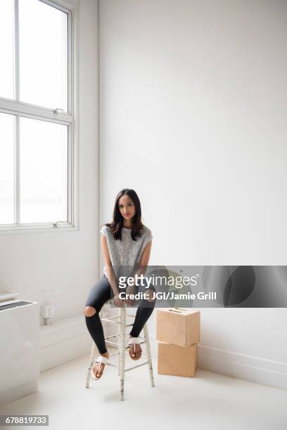 mixed race woman sitting on stool in corner - woman stool stock pictures, royalty-free photos & images