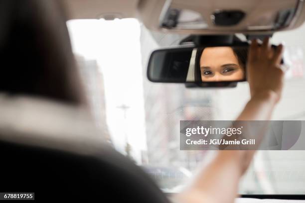 mixed race woman adjusting rear-view mirror in car - race car rear view mirror - fotografias e filmes do acervo