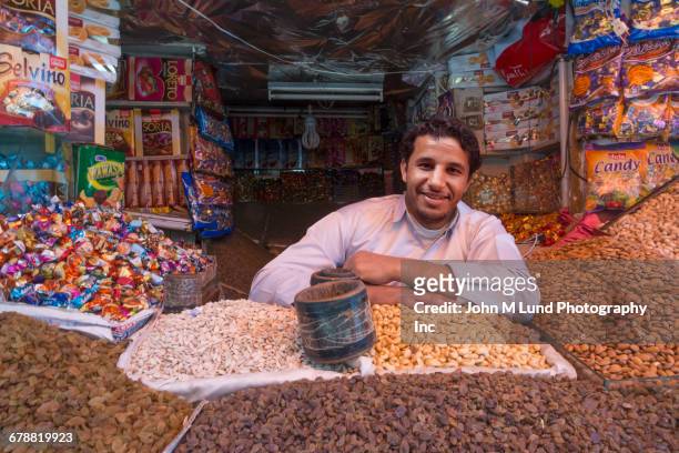 man surrounded by nuts and candy at market, saana, yemen - comida sana - fotografias e filmes do acervo