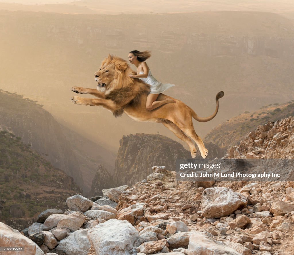 Mixed Race girl riding lion jumping on mountain