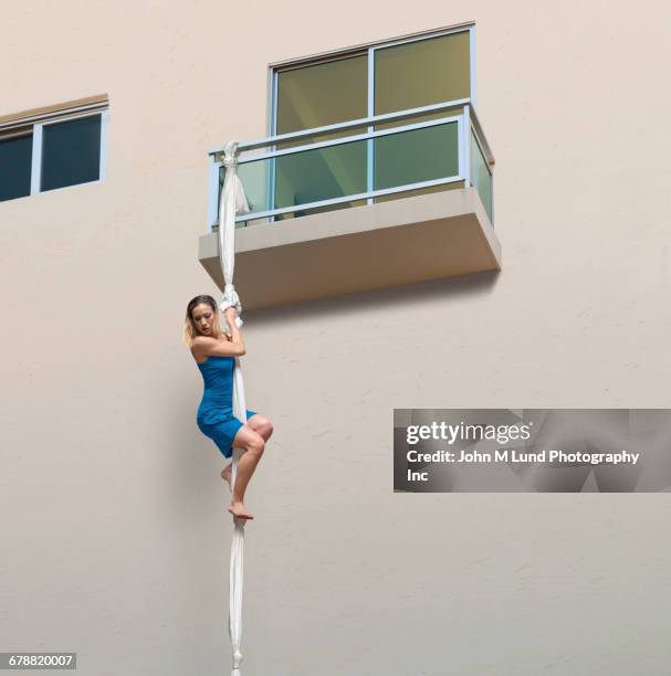 mixed race woman escaping balcony on knotted sheets - breakout stock-fotos und bilder