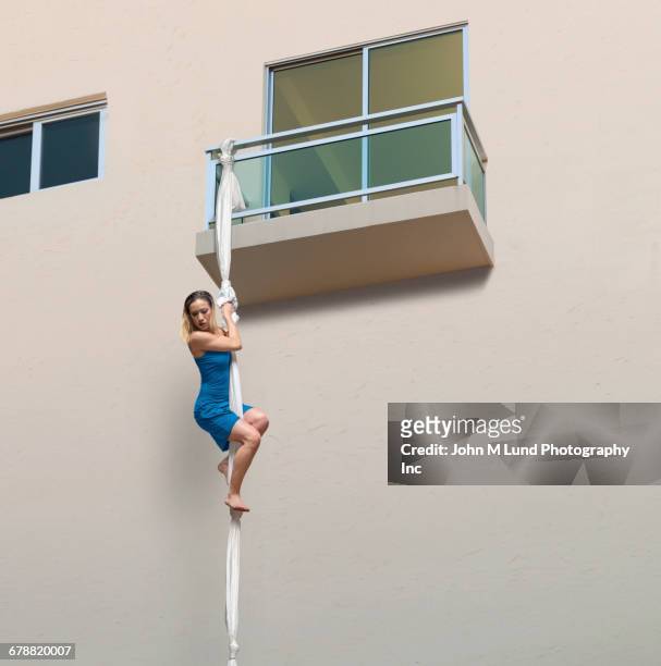 mixed race woman escaping balcony on knotted sheets - saída imagens e fotografias de stock