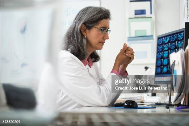 hispanic radiologist using computer at desk - medical research foto e immagini stock