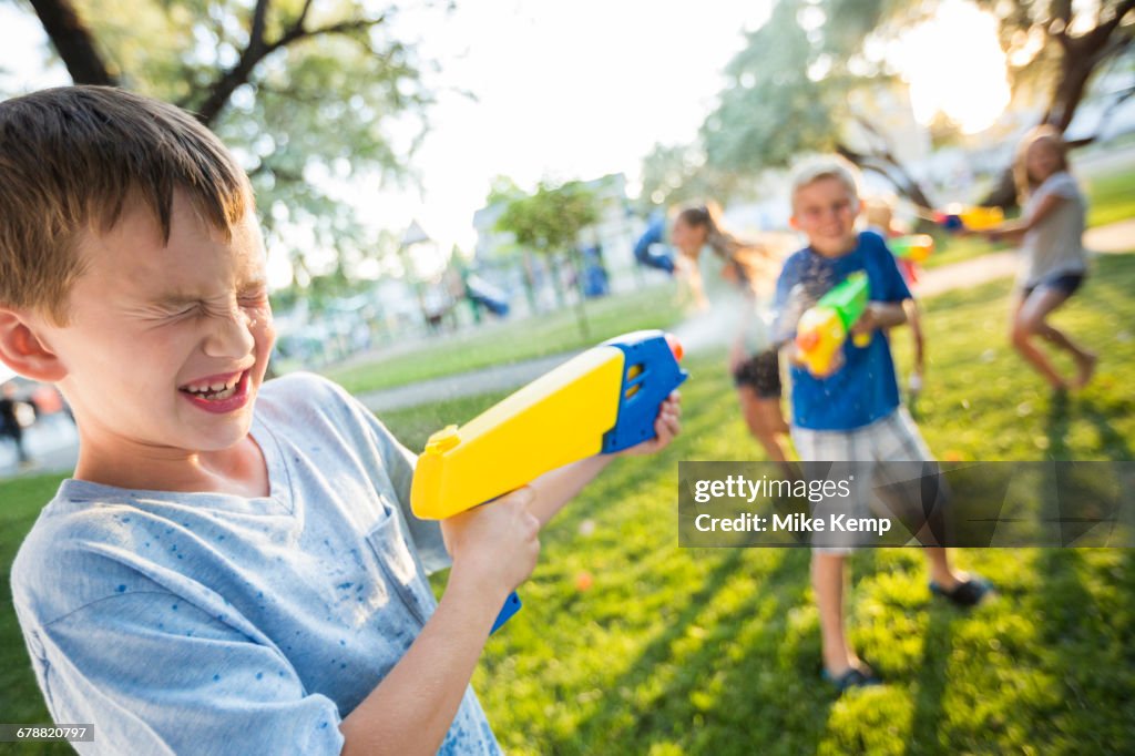 Caucasian boys and girls playing with squirt guns