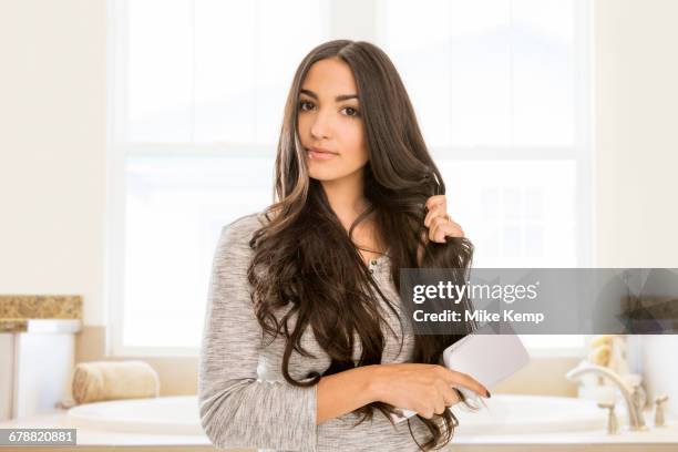 mixed race woman brushing hair in bathroom - woman hair stock pictures, royalty-free photos & images