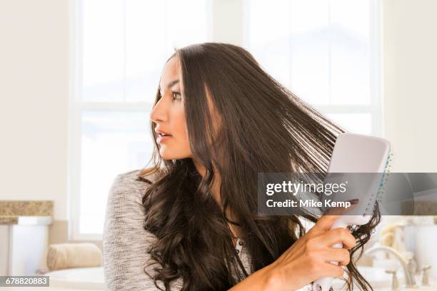 mixed race woman brushing hair in bathroom - hairbrush 個照片及圖片檔