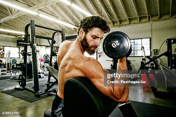 mixed race man lifting dumbbell in gymnasium - curly hair foto e immagini stock