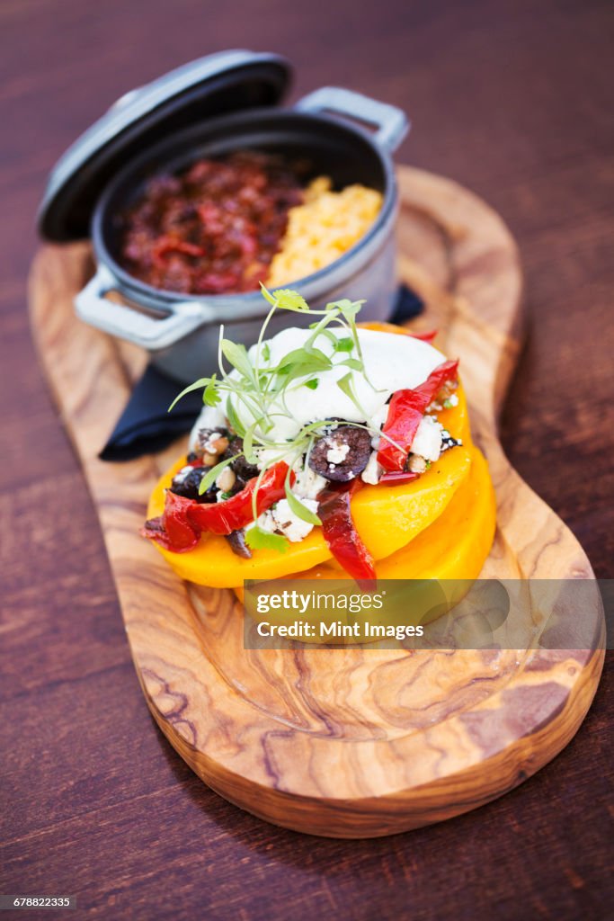 The Red Lion village public house food dishes. Trencher with a small pot of stew and a stack of fresh vegetables and a sour cream garnish.