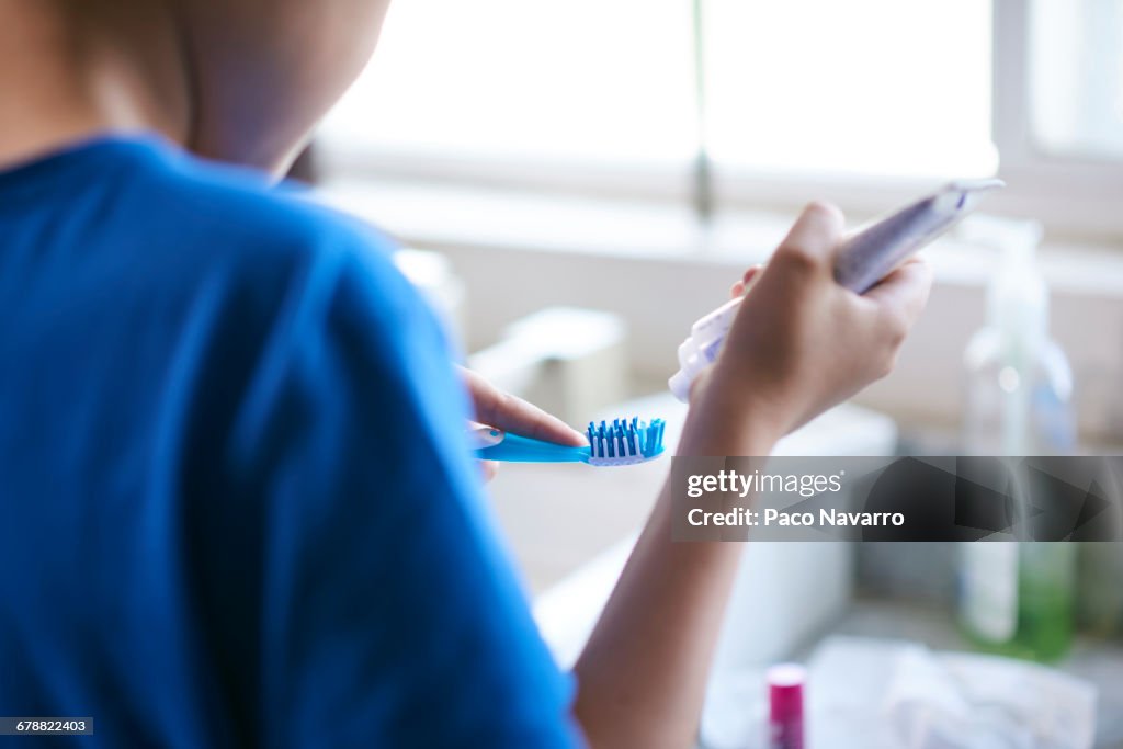 Hispanic by squeezing toothpaste onto toothbrush