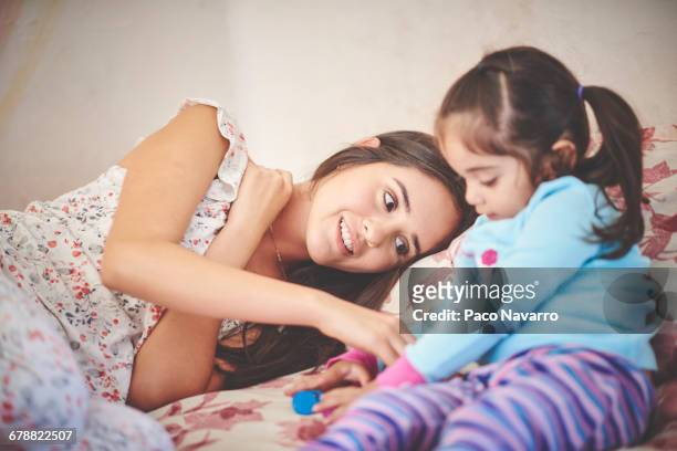 hispanic mother playing with daughter on bed - zapopan stock pictures, royalty-free photos & images