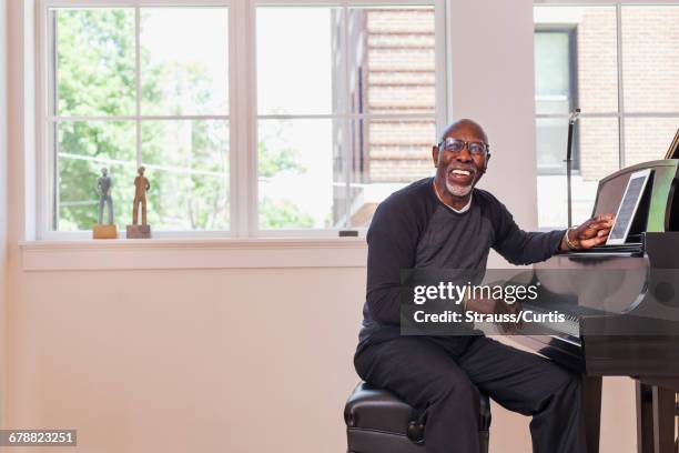 man sitting at piano with digital tablet near window - pianist stock pictures, royalty-free photos & images