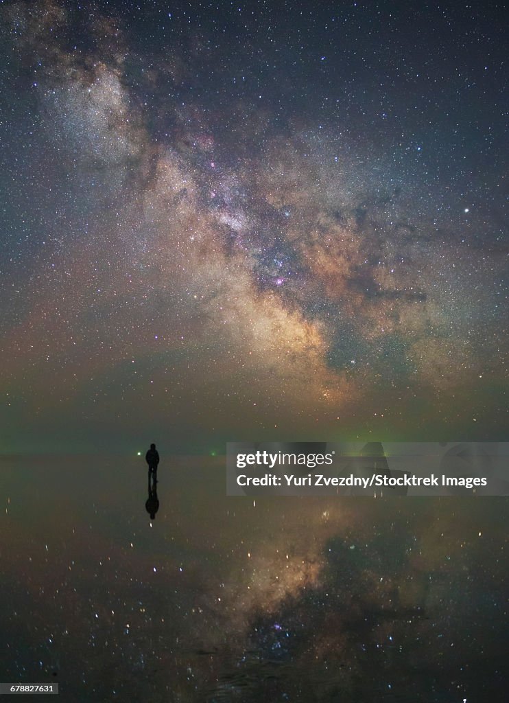 Man stands alone on Lake Elton in Russia under the center of the Milky Way.