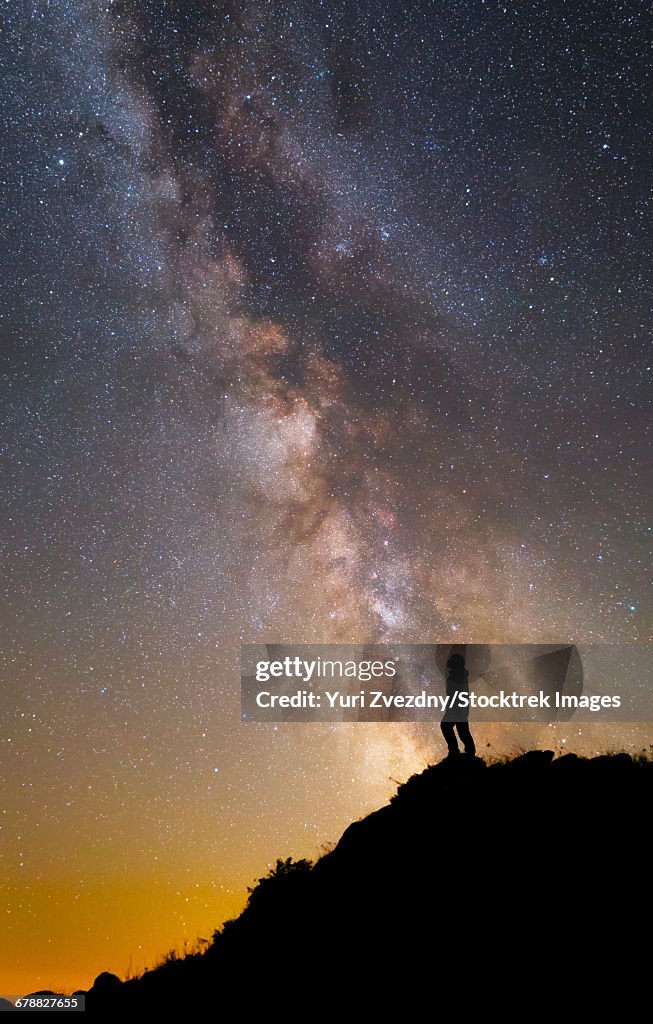 A man on a mountain under the Milky Way on the Lago-Naki plateau in Russia.