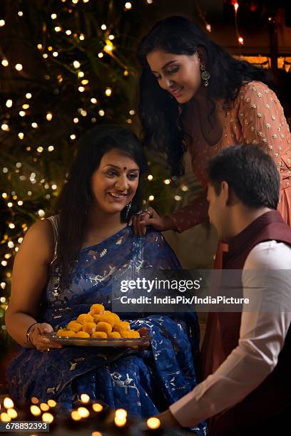 woman with her daughter and son-in-law celebrating diwali - laddoo stock pictures, royalty-free photos & images