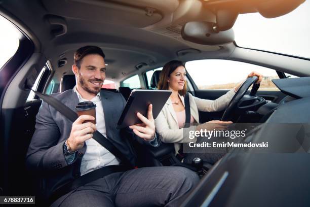 homme d’affaires à l’aide d’une tablette numérique tout en femme d’affaires, conduire une voiture - conduite responsable photos et images de collection