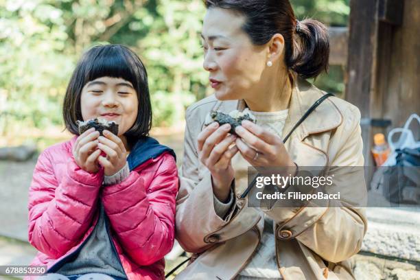 japanese mother and daughter eating onigiri together - rice ball stock pictures, royalty-free photos & images