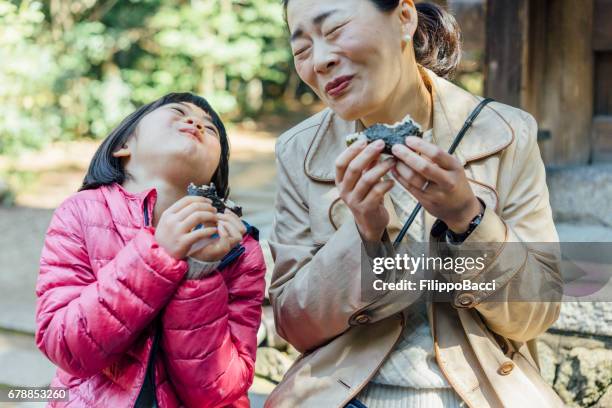 japanese mother and daughter eating onigiri together - rice ball stock pictures, royalty-free photos & images