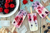 Mixed berry yogurt popsicles on a rustic wood background