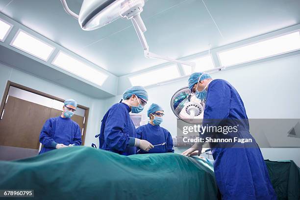operating room staff performing hospital surgery - sala de cirurgia com assistência imagens e fotografias de stock