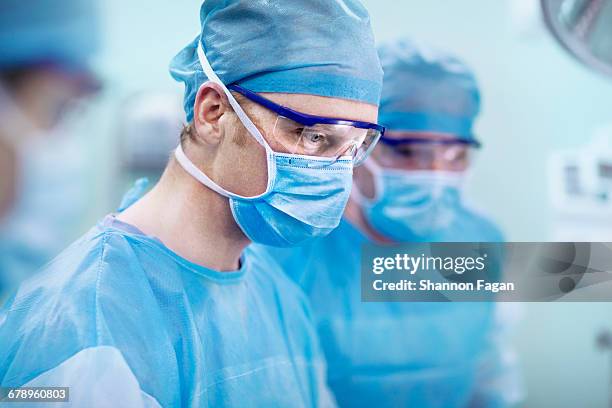 doctor looking at surgical table in operating room - blue surgical mask stock pictures, royalty-free photos & images