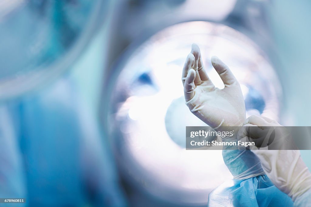 Surgeon adjusting glove in operating room