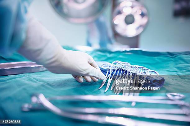 reaching for surgical tools in operating room - 外科用ハサミ ストックフォトと画像